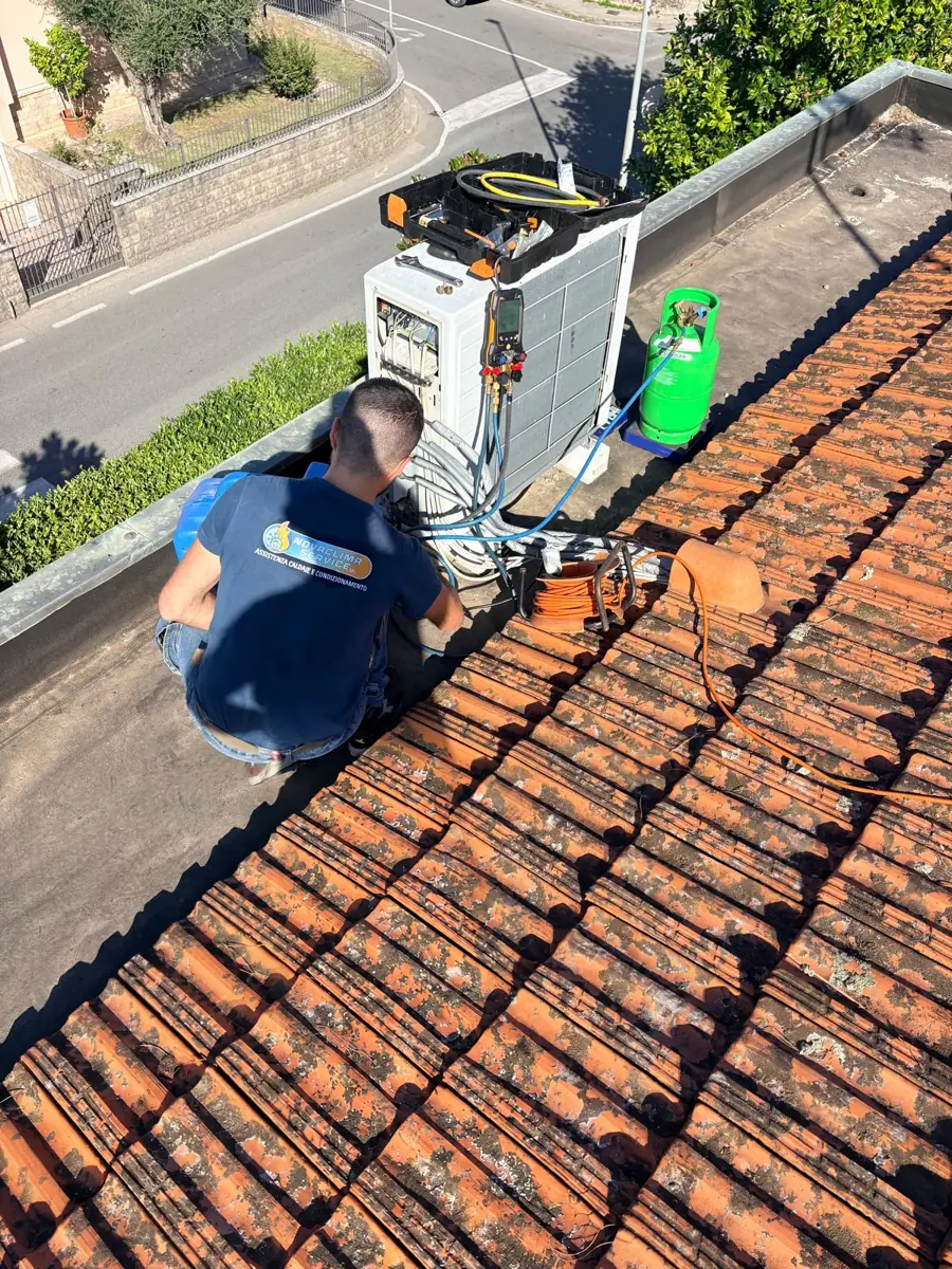 Tecnico Novaclima sul tetto mentre controlla il gas refrigerante di un'unità esterna con manometro digitale
