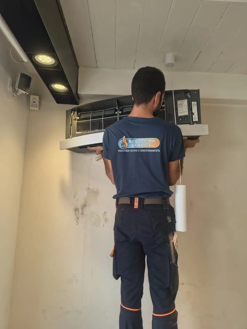 Tecnico Novaclima Service apre l'unità interna di un climatizzatore per la pulizia dei filtri